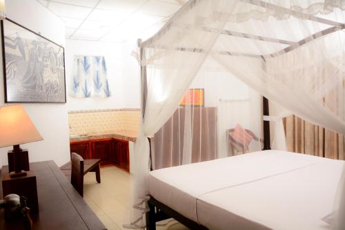 1 dormitorio con 1 cama blanca con dosel en YKD Tourist Rest Hikkaduwa, en Hikkaduwa