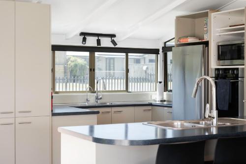 a kitchen with a sink and a refrigerator at Pukehina Estuary Sunset Views Holiday Home in Pukehina