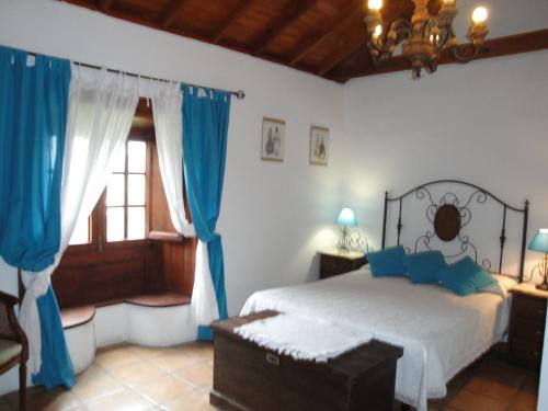 バジェエルモソにあるCasa Rural Guaidilのベッドルーム1室(青いカーテン、窓付)