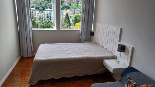 a bedroom with a bed and a large window at ACONCHEGO DA SERRA in Teresópolis