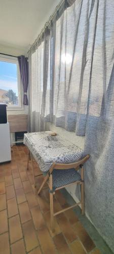 Cette chambre dispose d'une table et d'une fenêtre avec des rideaux. dans l'établissement Appartement face à la mer dans le charmant village de Sausset-les-pins, à Sausset-les-Pins