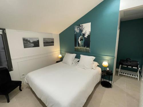 um quarto com uma cama branca e uma parede azul em La Petite Maison de Giverny Chambres de charme Gîte 5 étoiles au Cœur du village em Giverny