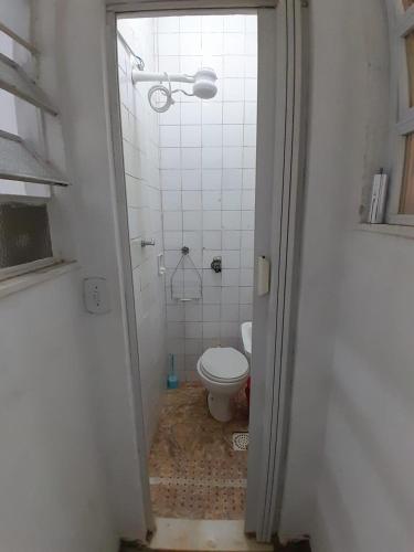 een badkamer met een toilet en een witte tegelmuur bij Quarto em Villa Jardim Botânico in Rio de Janeiro