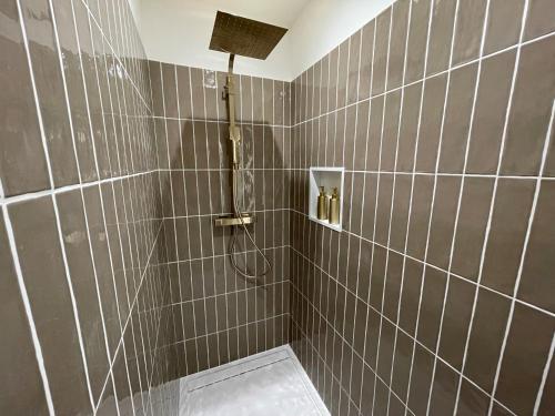 uma casa de banho com um chuveiro com paredes em azulejos cinzentos em La Petite Maison de Giverny Chambres de charme Gîte 5 étoiles au Cœur du village em Giverny