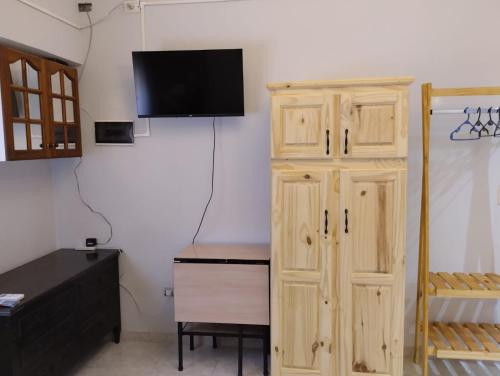 Habitación con armario de madera y TV en la pared. en Apartamento completo en Buenos Aires en Buenos Aires