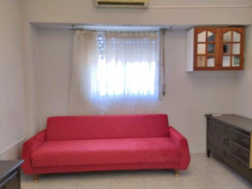 un sofá rojo en una sala de estar con ventana en Apartamento completo en Buenos Aires en Buenos Aires