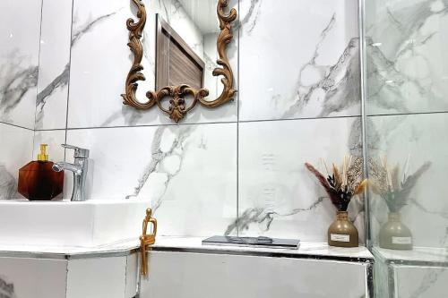 baño con paredes de mármol, lavabo y espejo en Central Buxton apt in Spring Gardens, en Buxton