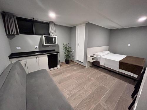 een kleine kamer met een bed en een keuken bij Terrazas Hotel in Curitiba