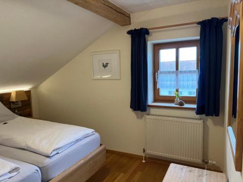 a bedroom with a bed and a window with blue curtains at Gut Schwarz-n Hof Ferienwohnungen in Bad Griesbach
