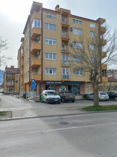 a large yellow building with cars parked in a parking lot at Lavander in Banja Luka