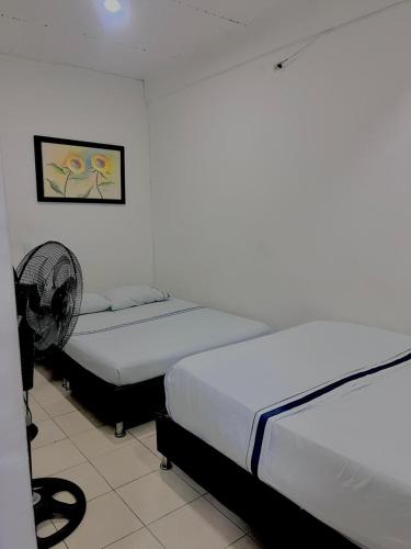 Cette chambre comprend deux lits et un ventilateur. dans l'établissement Hotel Viva Villavicencio, à Villavicencio