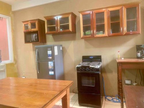 a kitchen with a refrigerator and a stove and a table at Casa 4 a 5 minutos del IRTRA in Retalhuleu