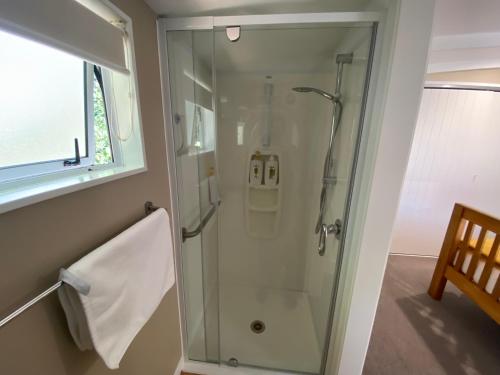 a shower with a glass door in a bathroom at The cottage at the Gables in Motueka
