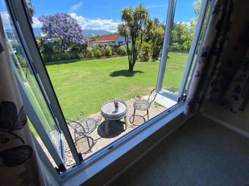 a window view of a patio with a table and chairs at The cottage at the Gables in Motueka