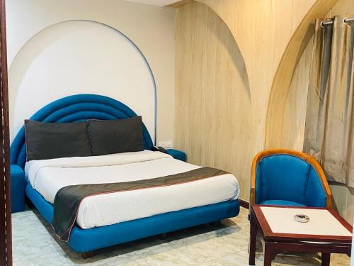 um quarto com uma cama azul e uma cadeira em THE ROYAL PRESIDENCY INN em Lucknow