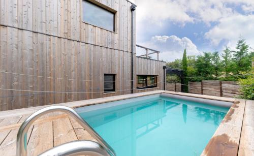 une maison avec une piscine à côté d'un mur en bois dans l'établissement Magnifique villa bois à Lacanau port, à Lacanau