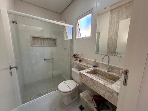 a bathroom with a toilet and a shower and a sink at Casas CostaMar in Caraguatatuba