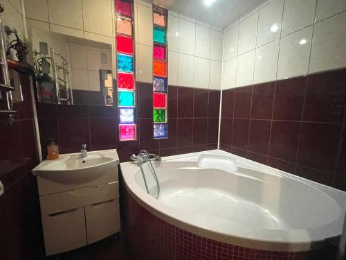 聶伯城的住宿－Гагарина Нагорка 2 кв，带浴缸和水槽的浴室,配有彩色玻璃窗