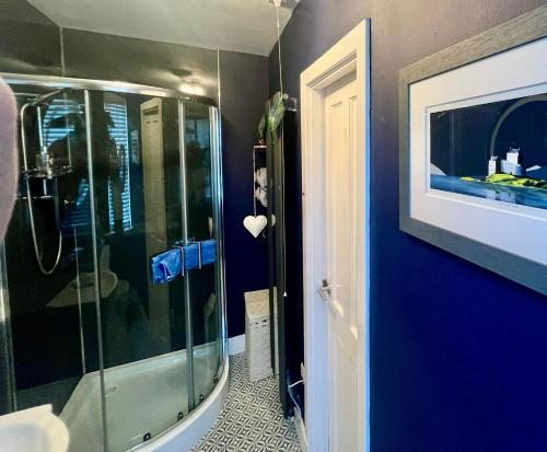 baño con ducha y pared azul en The Lodge Dunrowan en Kyle of Lochalsh