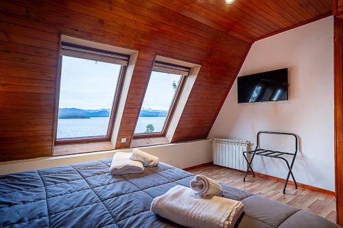 ein Schlafzimmer mit einem großen Bett und zwei Fenstern in der Unterkunft Destinar Apartments in San Carlos de Bariloche