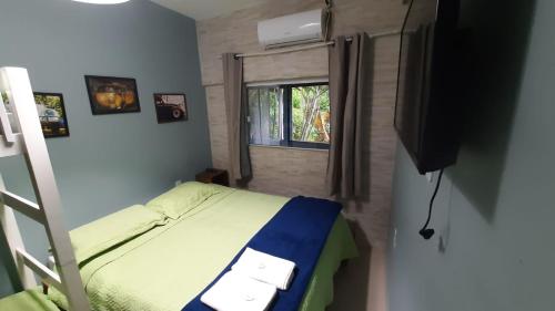 a small bedroom with a bed and a window at Pousada Casa da Maga - Centro in Blumenau