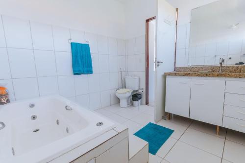 a white bathroom with a tub and a toilet at Casa com piscina a 5 min da praia em Alagoas in Barra de Santo Antônio