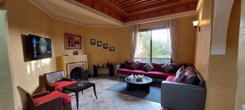 a living room with a red couch and a fireplace at Les Jardins de la palmeraie in Marrakech