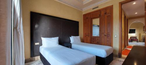a bedroom with two beds and a large headboard at Les Jardins de la palmeraie in Marrakech