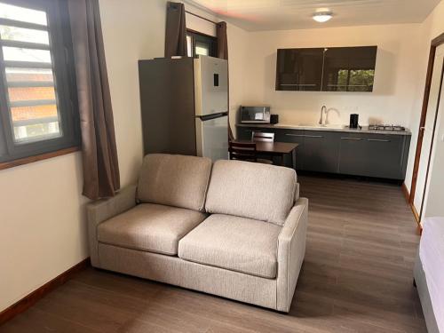 ein Wohnzimmer mit einem Sofa und einer Küche in der Unterkunft Parea Lodge Huahine Bungalow 2#FETI'A in Parea