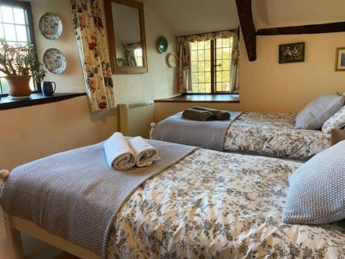 a bedroom with two beds with towels on them at Strongate Cottage Rural Retreat - near Bridport & Jurassic Coastline in Netherbury