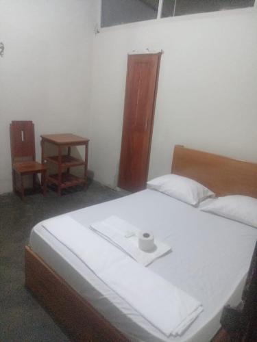 Un dormitorio con una gran cama blanca y una mesa en HOSPEDAJE BUENA VISTA IQUITOS, en Iquitos