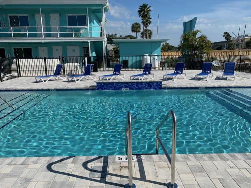 a swimming pool with blue chairs and a house at Sea Jay Motel and Marina in St Pete Beach