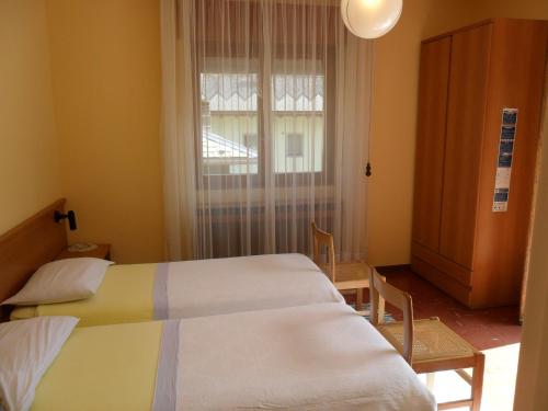 two beds in a room with a window at Albergo Motel Dosdè B&B in Grosio