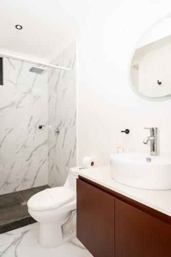 a white bathroom with a toilet and a sink at Acogedor apartamento en Ombu Huayacan in Cancún