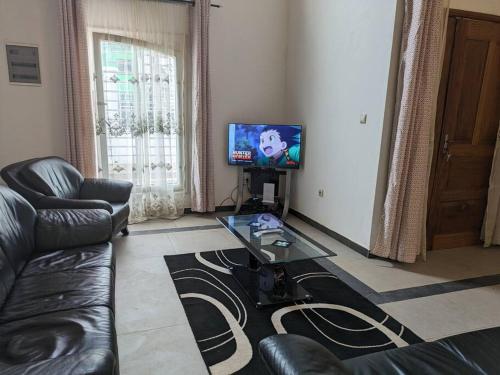 a living room with a couch and a table and a television at La Maison Blanche in Bafoussam