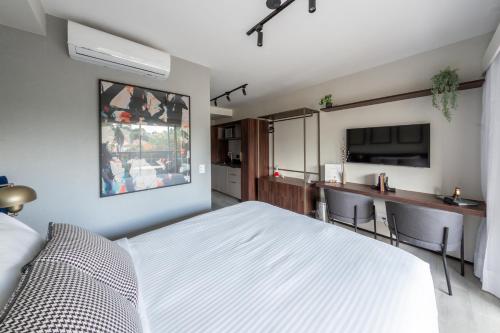 a bedroom with a white bed and a kitchen at Charlie On The Parc Ibirapuera Hotel in Sao Paulo
