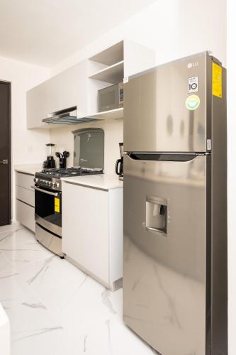 a kitchen with a stainless steel refrigerator and a stove at Acogedor apartamento en Ombu Huayacan in Cancún