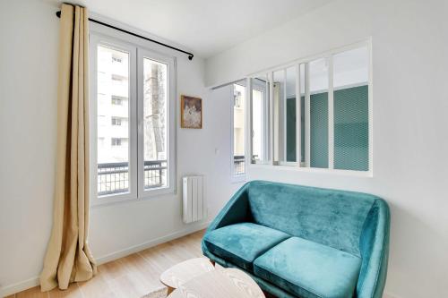 a blue chair in a room with windows at Small and modern apartment 11rd Paris in Paris