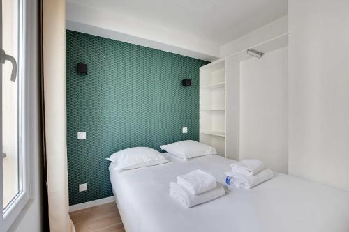 - une chambre avec 2 lits et un mur vert dans l'établissement Small and modern apartment 11rd Paris, à Paris