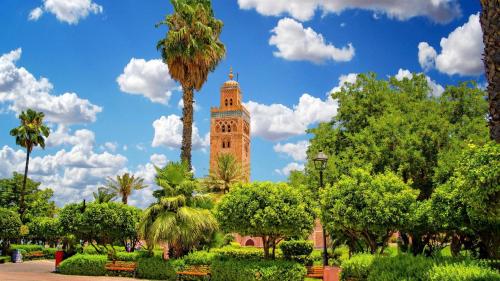 a clock tower in a park with a palm tree at Villa Taj Sofia & Spa in Marrakech