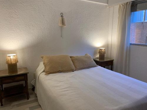 a bedroom with a white bed with two lamps on tables at Meridien in Punta del Este