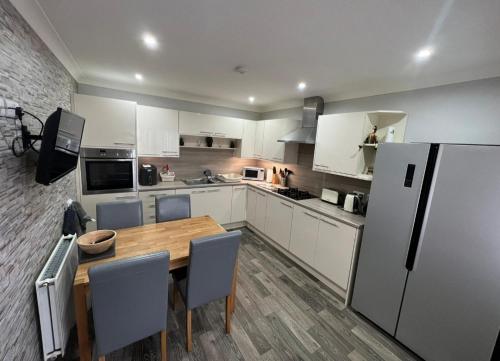 a kitchen with a wooden table and a refrigerator at 5 Riverside Place Thurso. 2 bed, 2 bathrooms. in Thurso