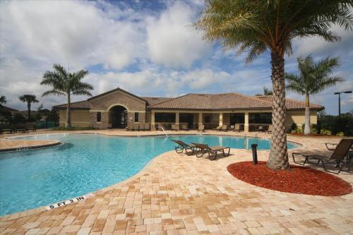a swimming pool with a palm tree in front of a house at Caddy's Corner! Golf Course Views! Located in River Strand Golf & Country Club in Bradenton