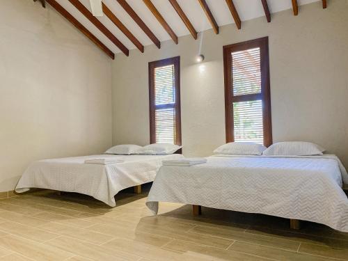two beds in a room with two windows at CABAÑA TAYRONACA in Calabazo
