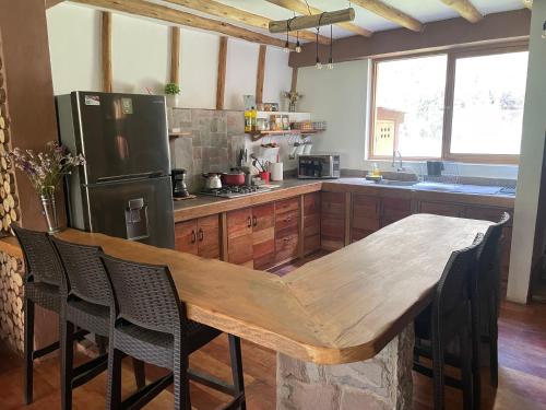 uma cozinha com uma mesa de madeira e um frigorífico em Casa Mayuwasi Cuzco - Valle Sagrado de los Incas em Calca