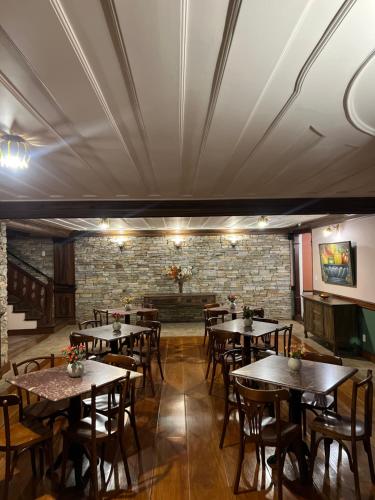 a restaurant with tables and chairs and a brick wall at Pousada Sinhá Olímpia in Ouro Preto