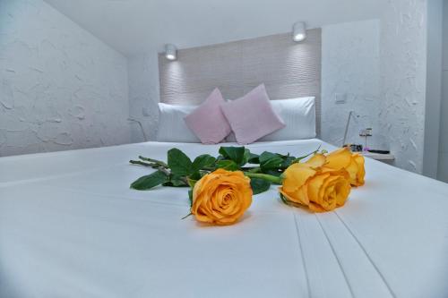 a white bed with a bouquet of yellow roses on it at T-Homes - Cuenca in Madrid