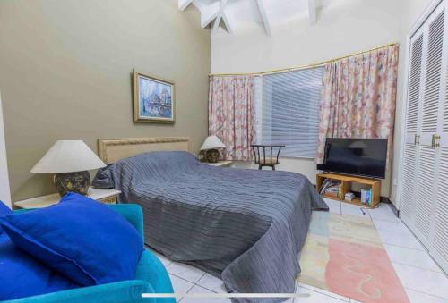 LaGita Carita Villa في كاريتا: غرفة نوم بسرير وتلفزيون بشاشة مسطحة