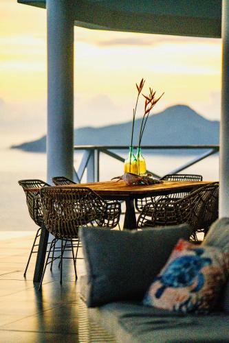 a table and chairs on a balcony with a view of the water at Villa Club Tropicana Carana with infinity pool in Machabee