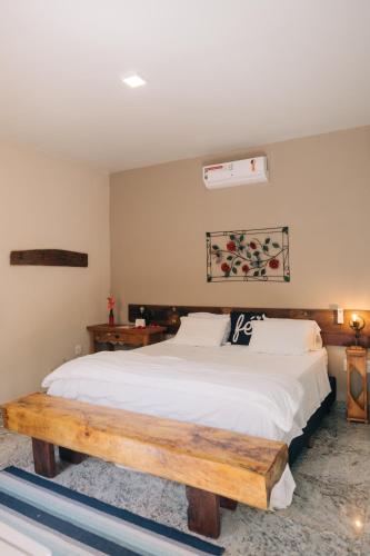 a bedroom with a large bed with a wooden bench at Pousada Adega Cipo in Serra do Cipo